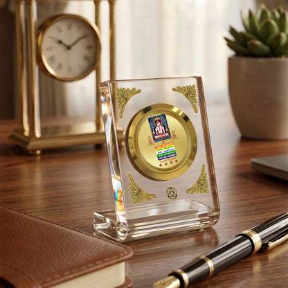 Diviniti 24K Gold Plated Lord Adinath acrylic frame on a wooden desk with a watch and notebook.
