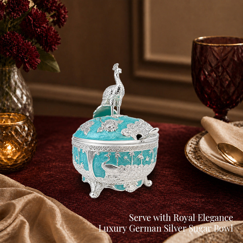 Diviniti German Silver Peacock Sugar Bowl with Spoon showcasing a luxurious turquoise blue finish on an elegant dining table.