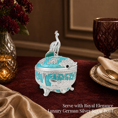 Diviniti German Silver Peacock Sugar Bowl with Spoon showcasing a luxurious turquoise blue finish on an elegant dining table.