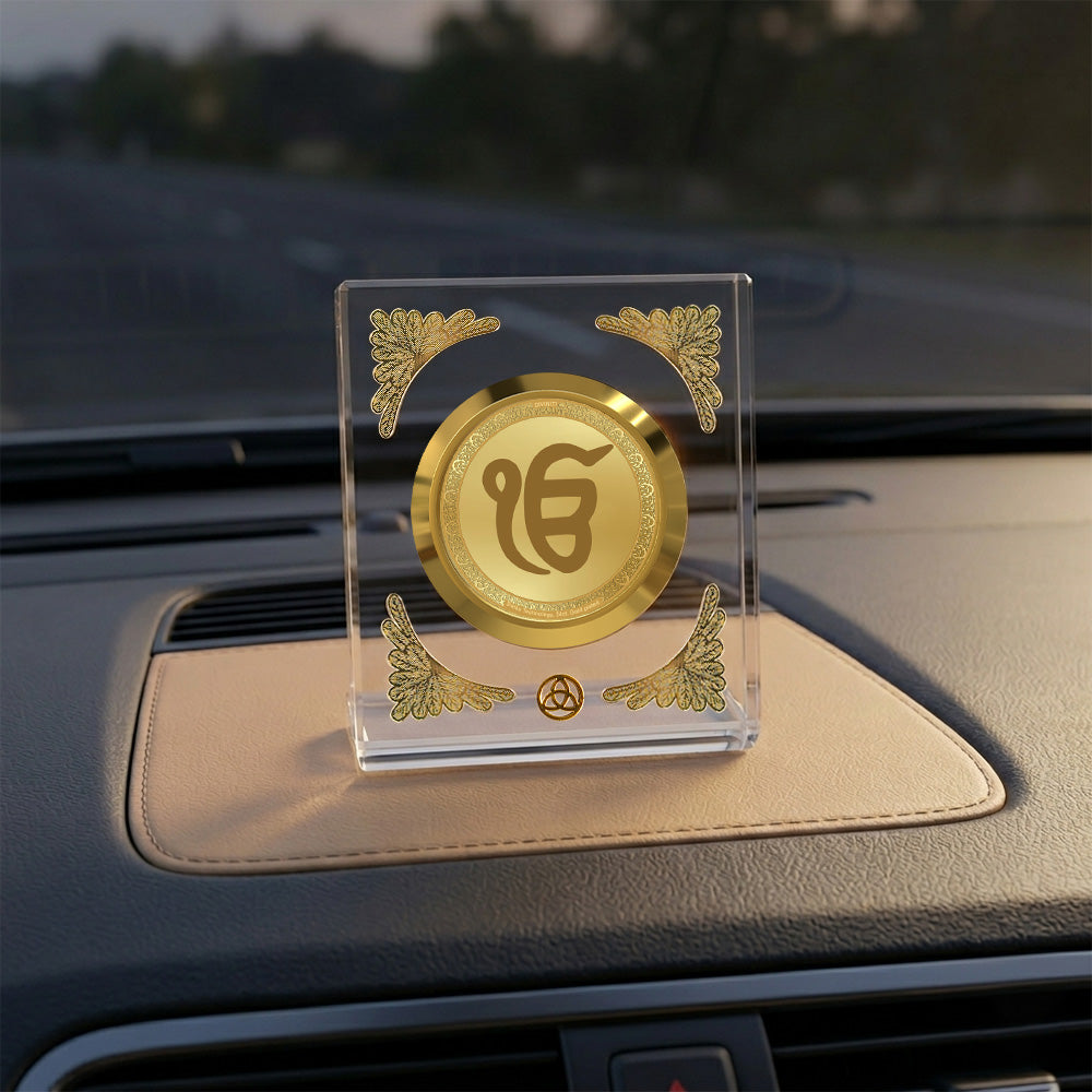 Ik Omkar car dashboard frame in crystal-clear acrylic with gold detailing on a car interior.