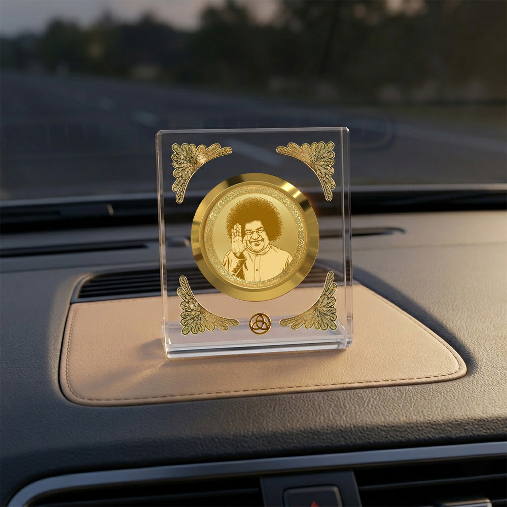 Satya Sai Baba car dashboard frame in crystal-clear acrylic with gold detailing on a car interior.