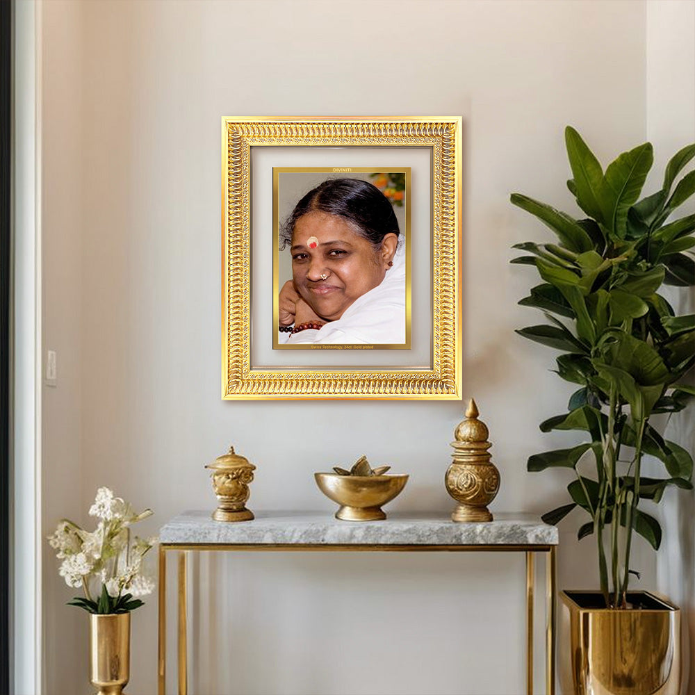 Mata Amritanandamayi framed portrait in an elegant gold frame on a console table with plants.