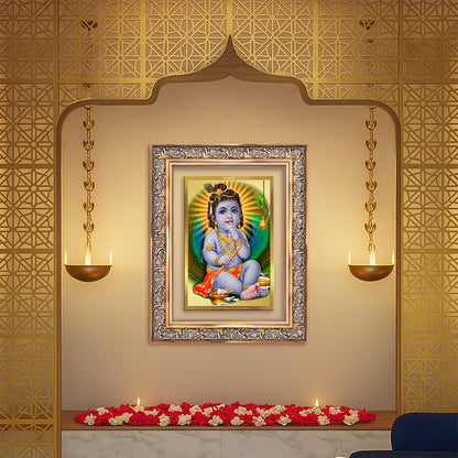 Baby Krishna gold photo frame displayed in a decorative wall setting with flowers and elegant lighting.
