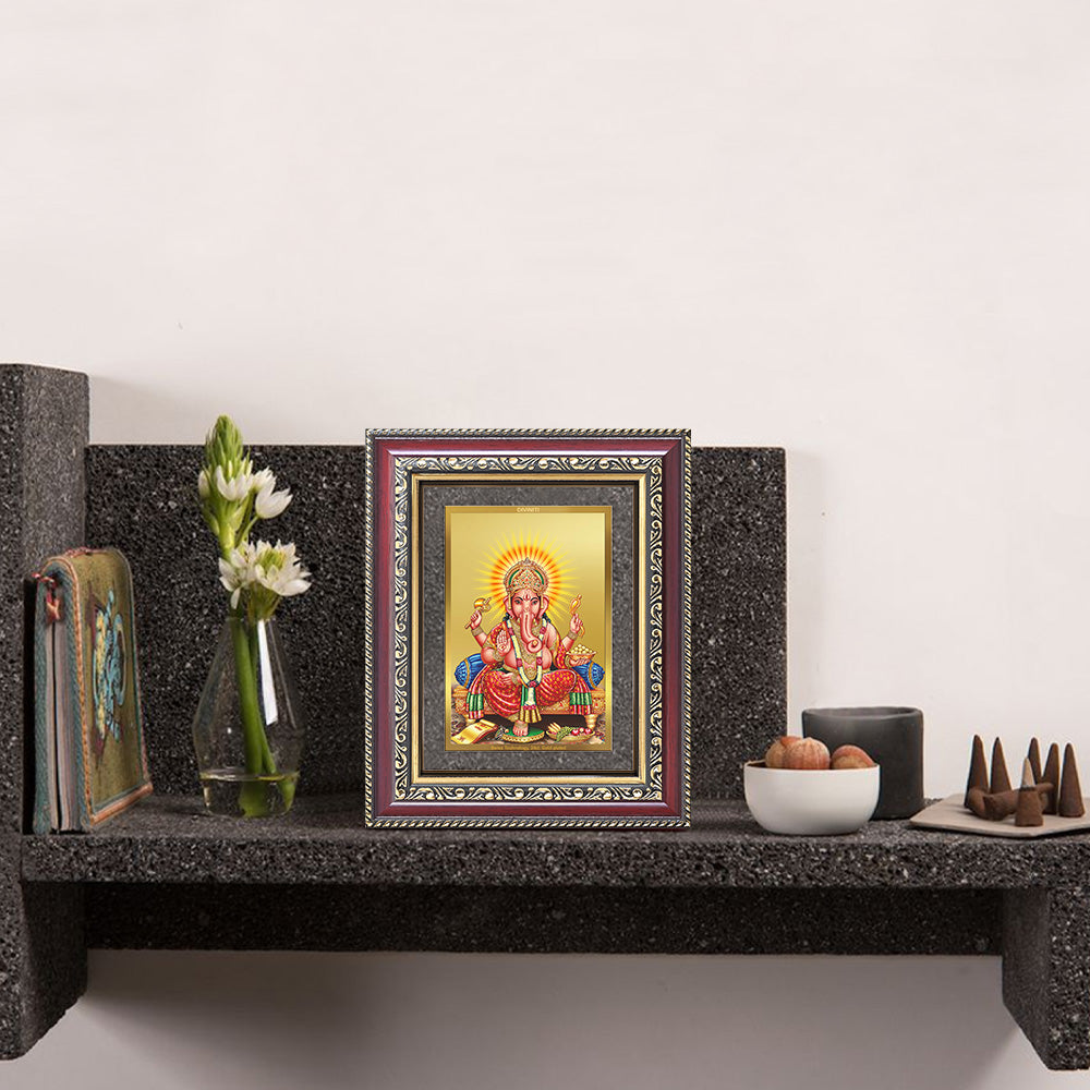 Lord Ganpati photo frame displayed on a wall shelf, featuring a 24K gold-plated foil frame with elegant spiritual décor elements.