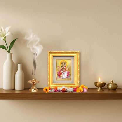 Gayatri Mata tabletop frame in 24K gold plated foil displayed on a shelf with decorative elements.