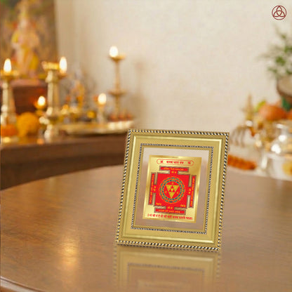 Kanak Dhara Yantra framed on a wooden table with a decorative background featuring warm lighting and spiritual elements.