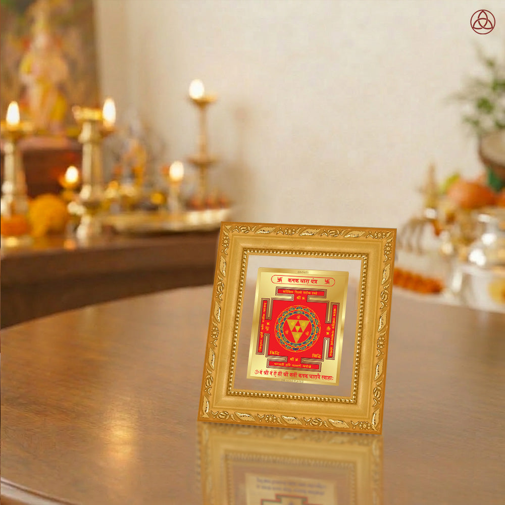 Kanak Dhara Yantra framed on a wooden table with a decorative background featuring warm lighting and spiritual elements.