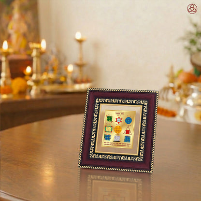 Navagraha Yantra displayed in a decorative frame on a wooden table, symbolizing planetary energies.