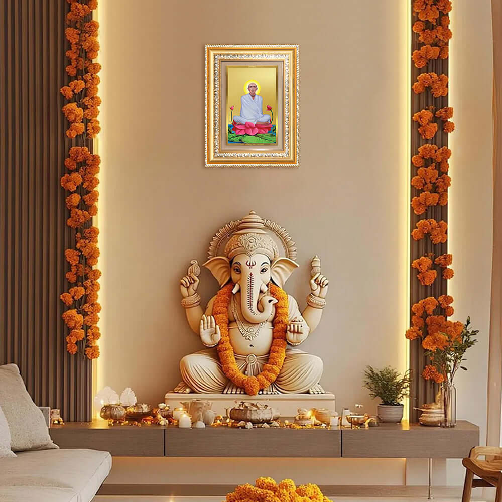 24K gold plated photo frame of Saint Ram Thakur displayed above a decorative Ganesh statue in a serene home decor setting.
